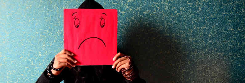 a person holding up a piece of paper with a sad face on it