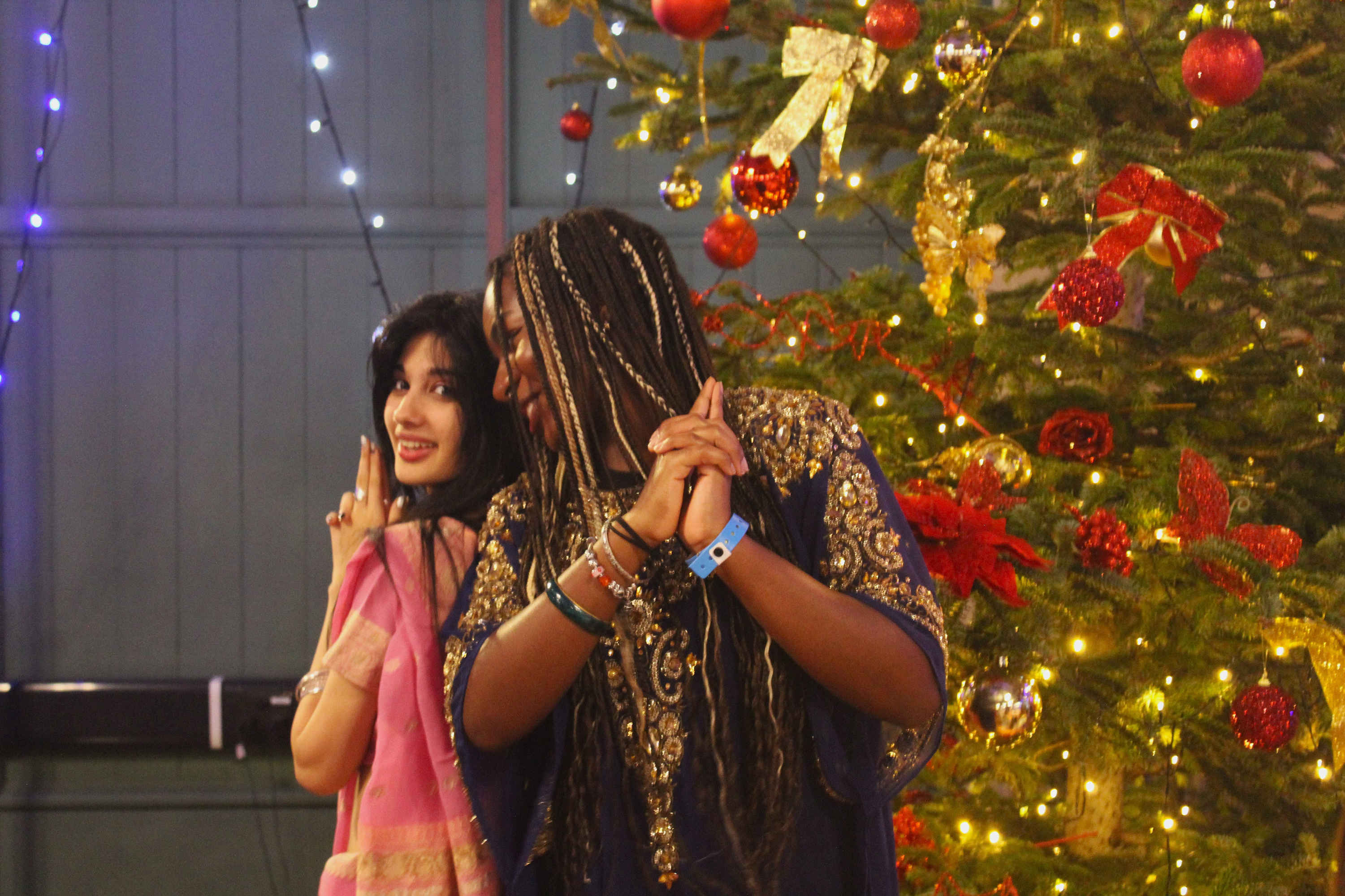 girls in cultural clothes pose with a christmas tree