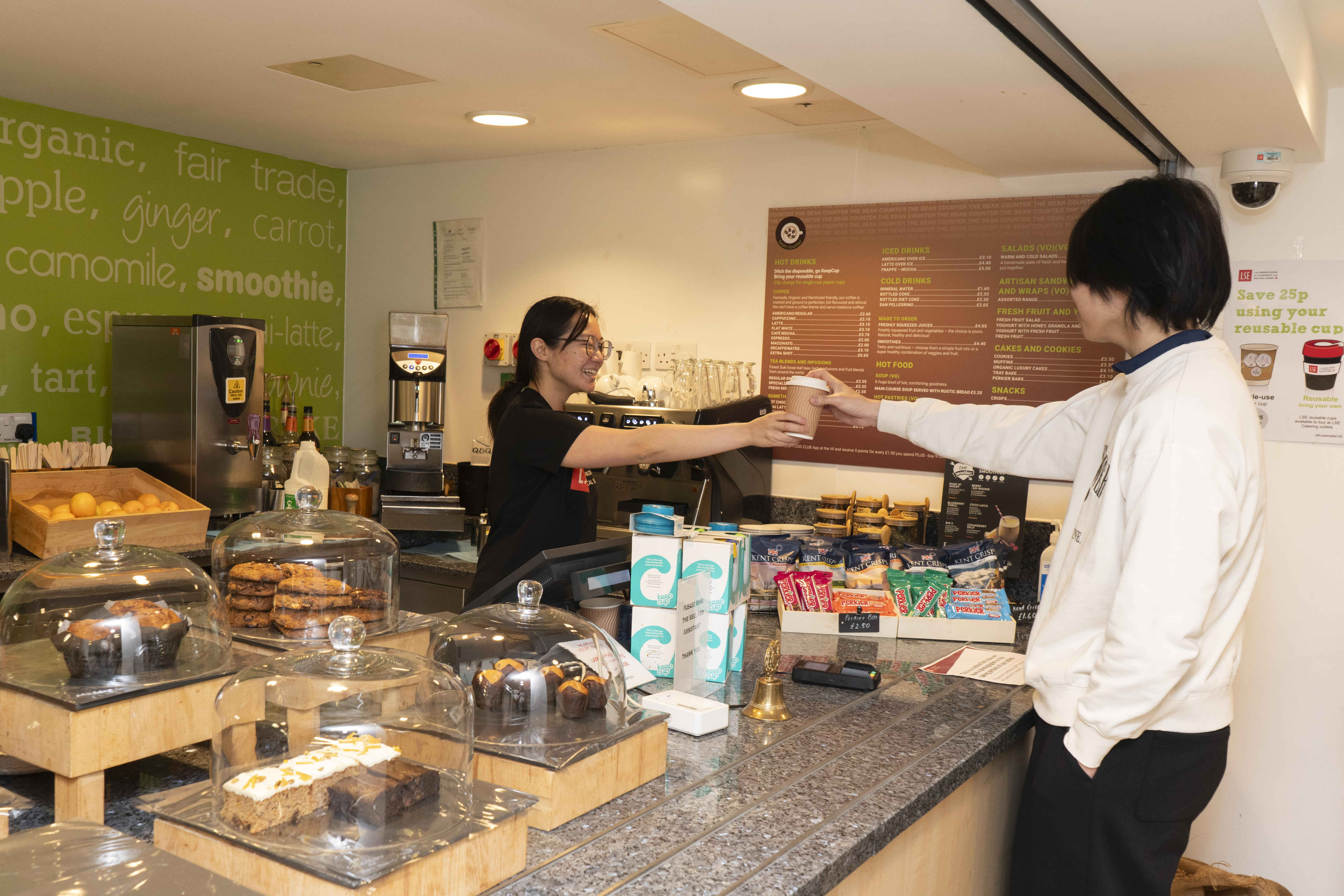 a barista handing a cup of coffee to a customer at a cafe